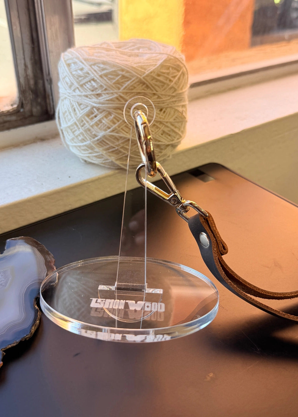 Yarn ball with a hook on a clear stand, window in the background