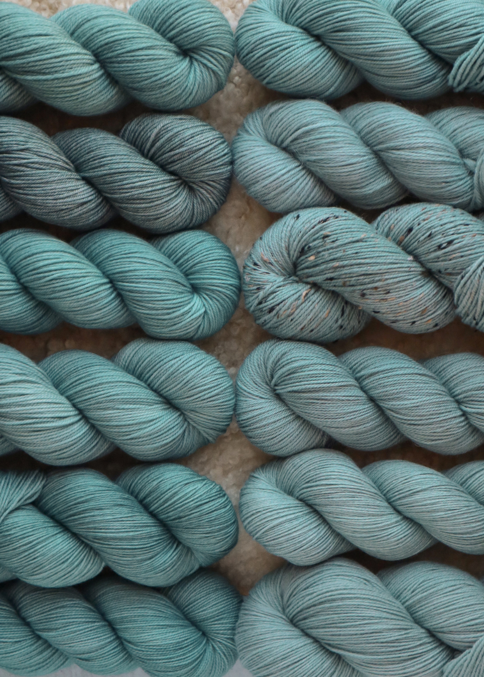 Multiple skeins of teal yarn on a textured surface